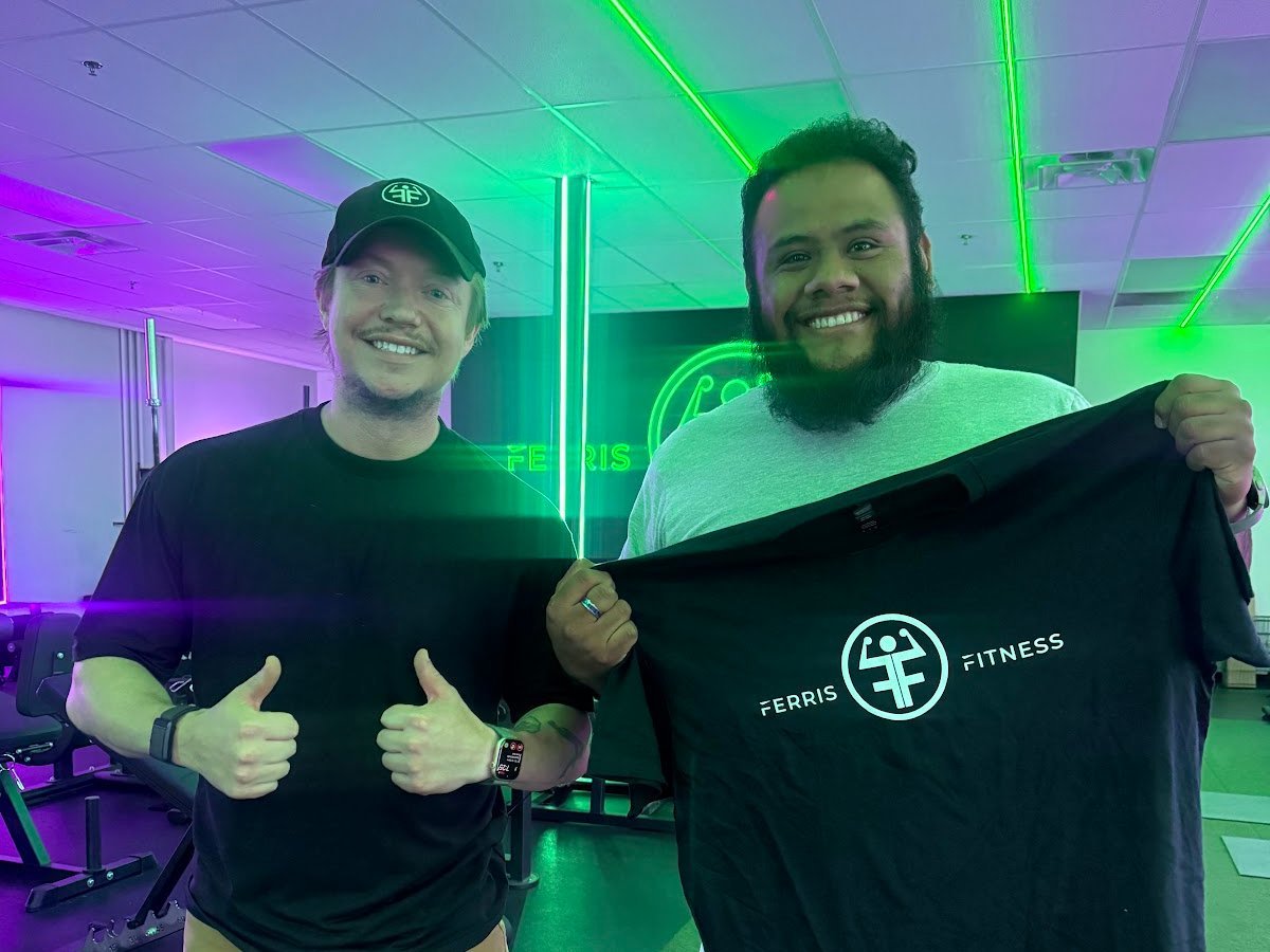Ferris Fitness coach and member celebrating with a Ferris Fitness shirt at the Duluth, GA gym